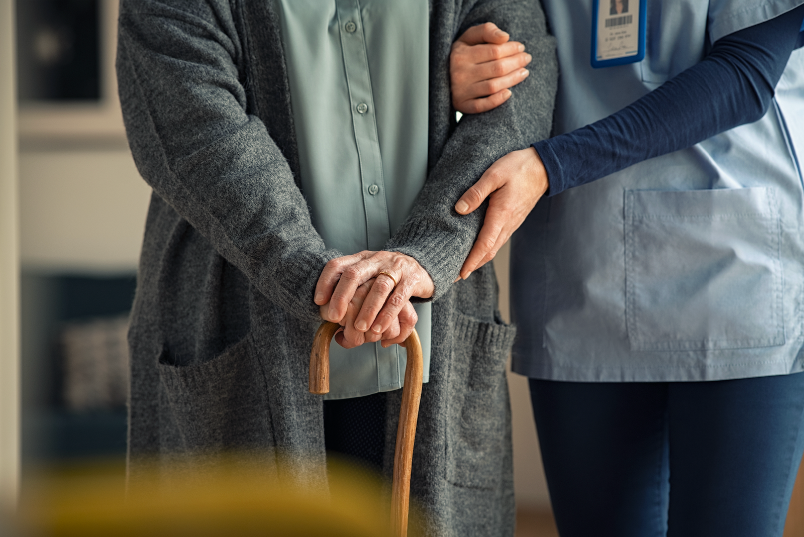Nurse helping elderly patient walk safely at home during a nurse home visit